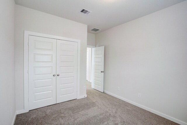 unfurnished bedroom with light colored carpet and a closet