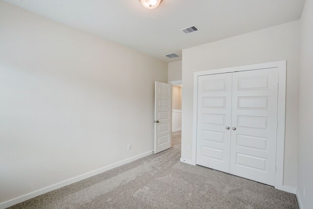 unfurnished bedroom with light carpet and a closet