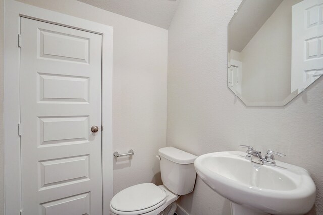 bathroom featuring sink, lofted ceiling, and toilet