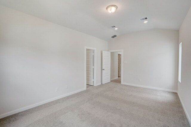 unfurnished bedroom with light carpet, a closet, and lofted ceiling