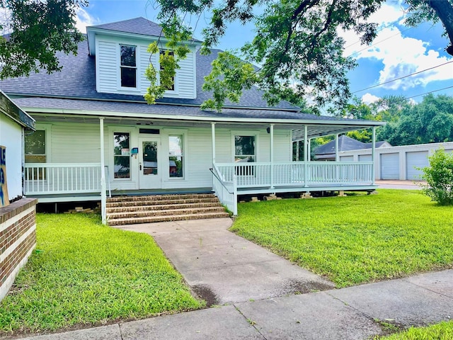 farmhouse inspired home featuring a front yard, a porch, and an outbuilding