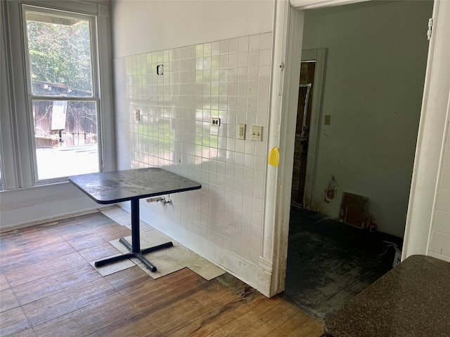 dining area featuring wood-type flooring and tile walls