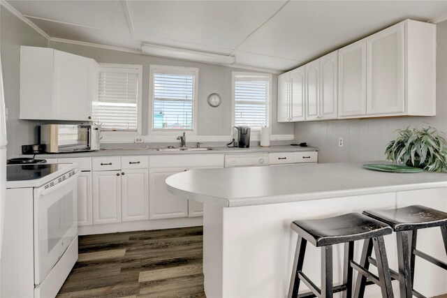 kitchen featuring dark hardwood / wood-style flooring, white appliances, white cabinets, a breakfast bar, and sink