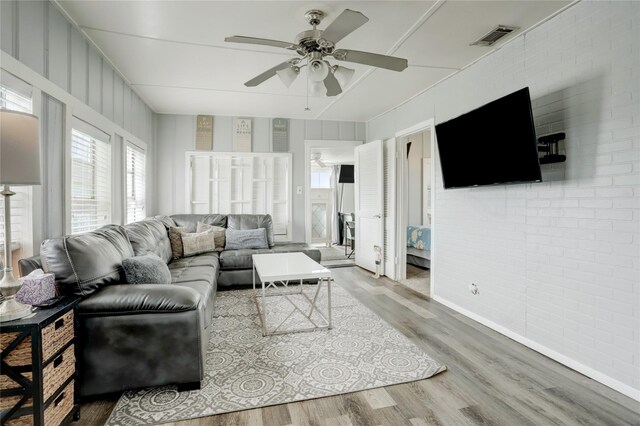 living room featuring brick wall, ceiling fan, and hardwood / wood-style floors