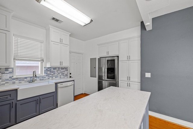 kitchen featuring light hardwood / wood-style floors, dishwasher, stainless steel refrigerator, white cabinets, and sink