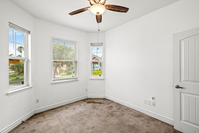 empty room featuring ceiling fan, a wealth of natural light, and light carpet