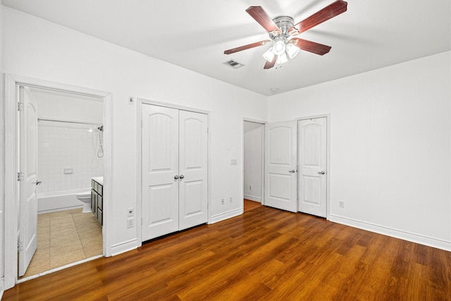 unfurnished bedroom featuring ceiling fan, ensuite bath, and hardwood / wood-style floors