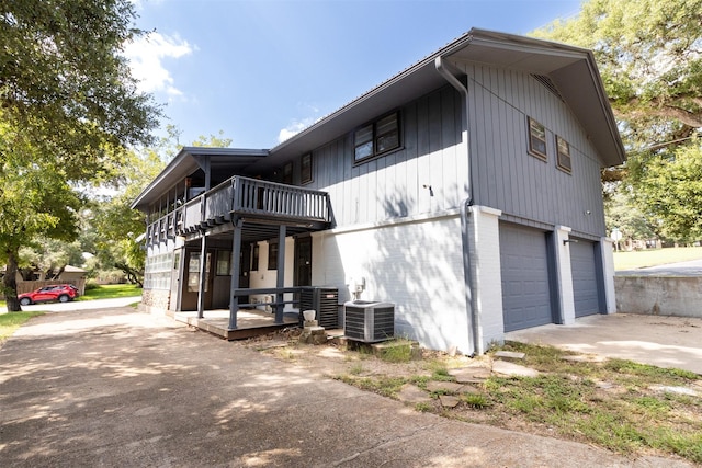 view of side of property with an attached garage, driveway, and central air condition unit