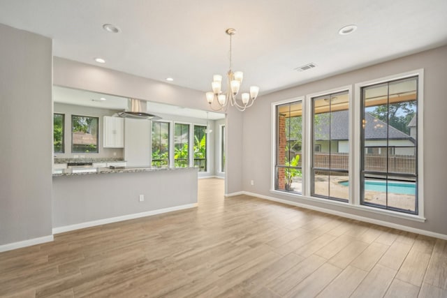 unfurnished living room with a notable chandelier and light hardwood / wood-style floors