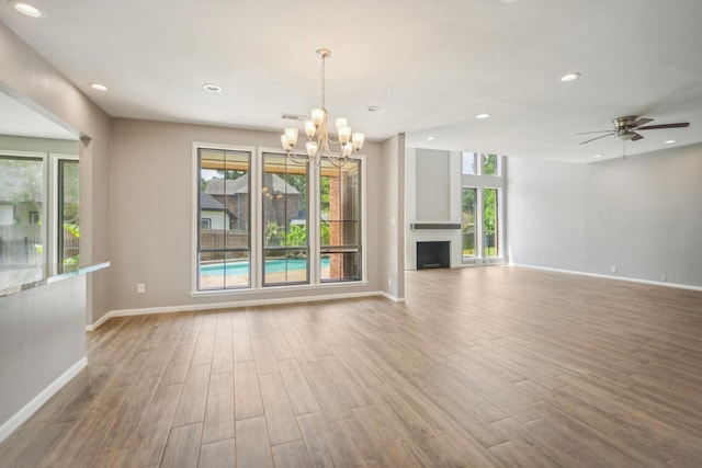 unfurnished living room with ceiling fan with notable chandelier and light wood-type flooring