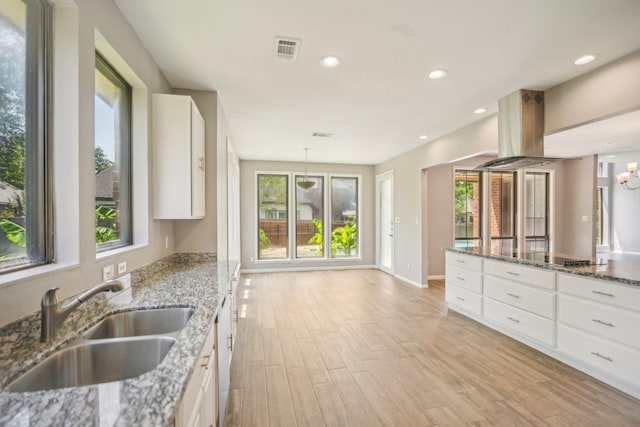 kitchen featuring white cabinets, light hardwood / wood-style flooring, light stone counters, and a wealth of natural light