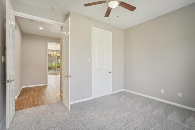 unfurnished bedroom featuring ceiling fan with notable chandelier and light carpet