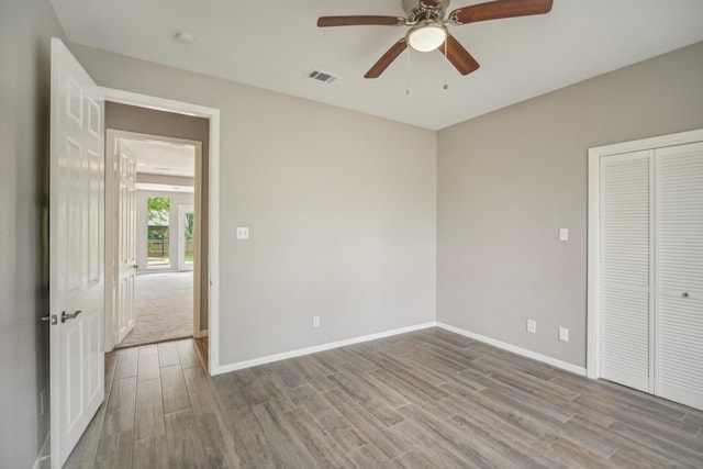 unfurnished bedroom with ceiling fan, a closet, and light wood-type flooring