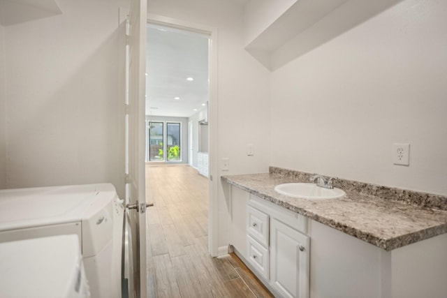 bathroom with wood-type flooring, vanity, and separate washer and dryer