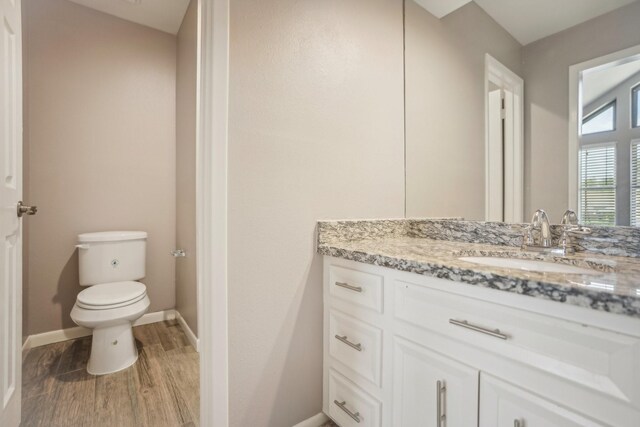 bathroom featuring toilet, vanity, and hardwood / wood-style flooring