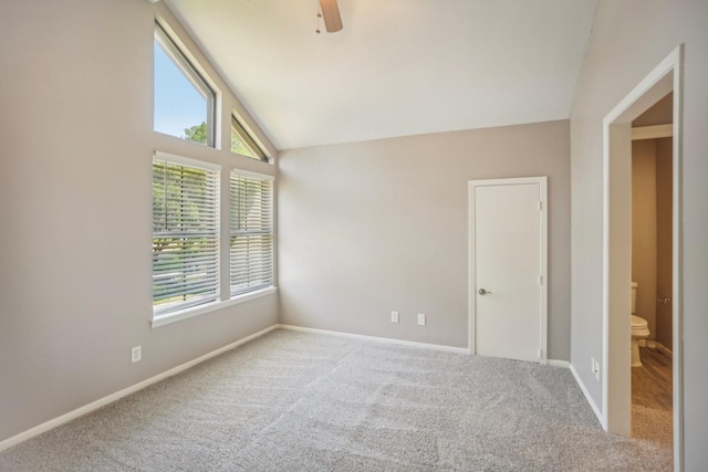 carpeted empty room featuring ceiling fan, a healthy amount of sunlight, and vaulted ceiling