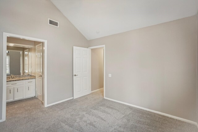 unfurnished bedroom with light carpet, high vaulted ceiling, ensuite bath, and sink