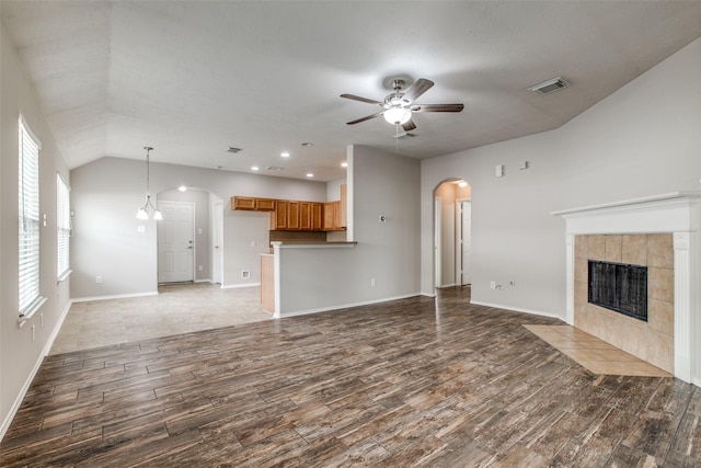 unfurnished living room featuring ceiling fan, dark hardwood / wood-style flooring, lofted ceiling, and a fireplace