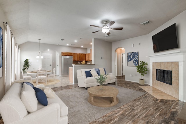 living room featuring hardwood / wood-style flooring, ceiling fan, a fireplace, and vaulted ceiling