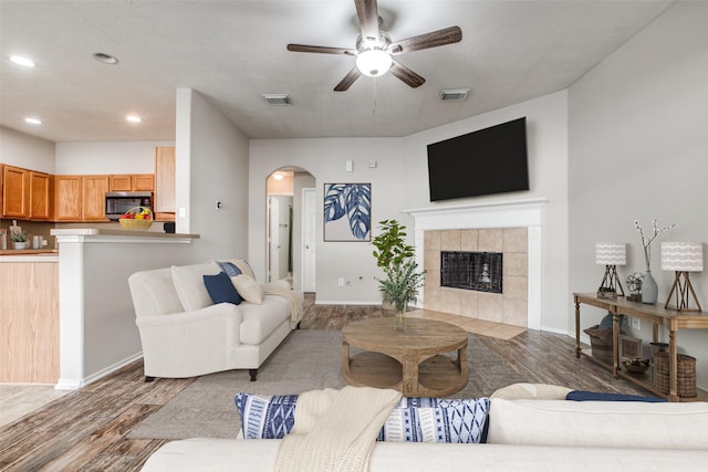 living room featuring a tiled fireplace, ceiling fan, and hardwood / wood-style flooring