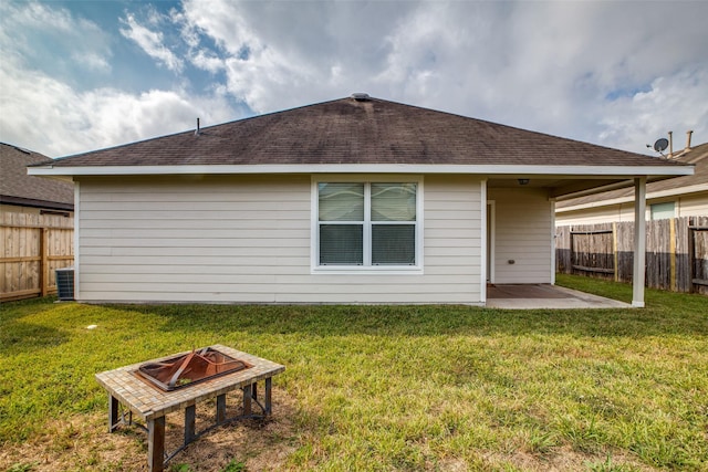 rear view of property featuring a lawn, cooling unit, a patio, and an outdoor fire pit