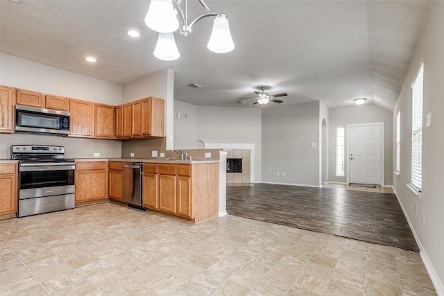 kitchen with hanging light fixtures, stainless steel appliances, lofted ceiling, ceiling fan with notable chandelier, and light wood-type flooring