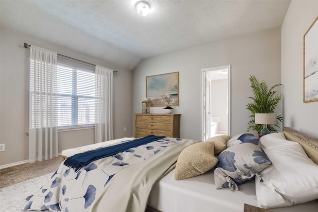 carpeted bedroom with a textured ceiling, connected bathroom, and vaulted ceiling