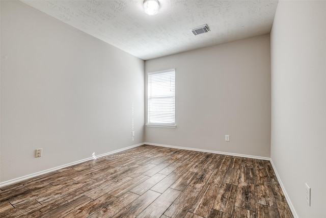 spare room with dark hardwood / wood-style floors and a textured ceiling