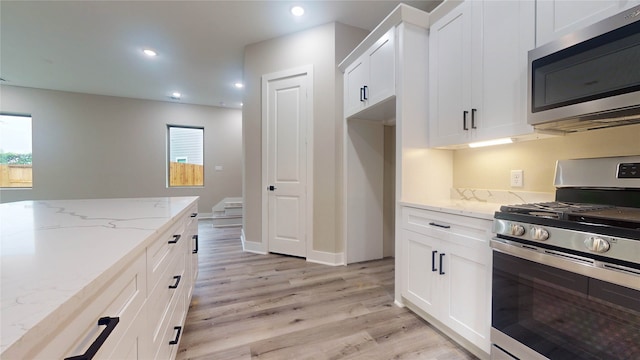 kitchen featuring stainless steel appliances, light hardwood / wood-style flooring, light stone counters, and white cabinets