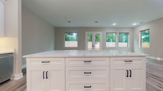 kitchen featuring light stone countertops, light hardwood / wood-style floors, white cabinets, and stainless steel dishwasher