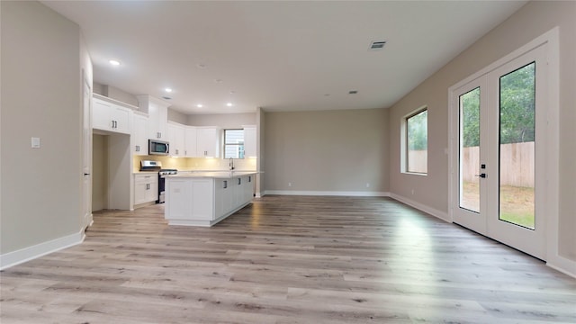 kitchen with appliances with stainless steel finishes, white cabinetry, light hardwood / wood-style floors, and plenty of natural light