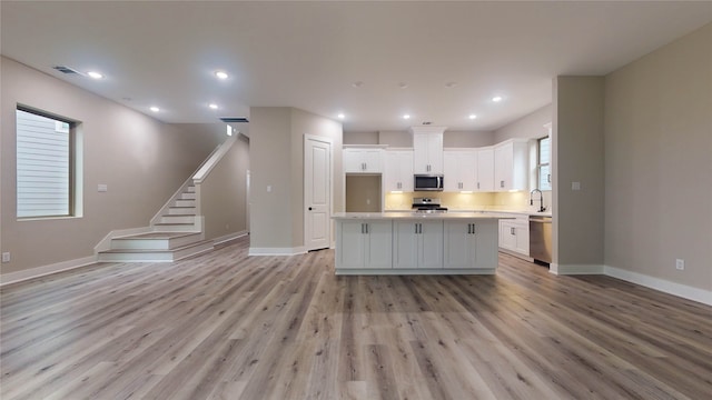 kitchen featuring a center island, white cabinetry, light wood-type flooring, and stainless steel appliances