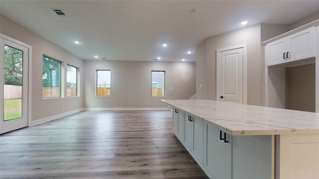 kitchen with a wealth of natural light, wood-type flooring, white cabinetry, and a kitchen island