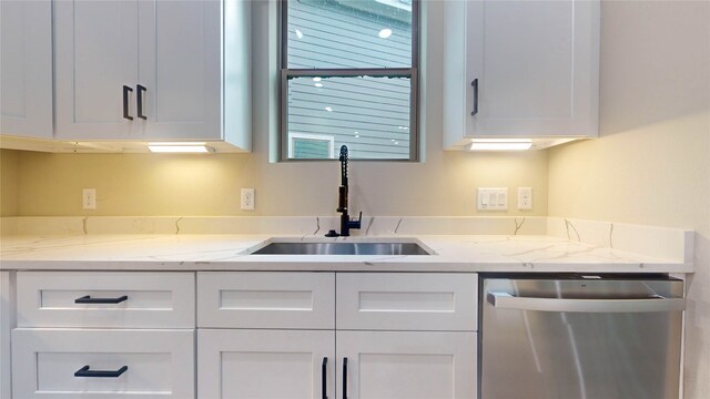 kitchen featuring white cabinets, sink, stainless steel dishwasher, and light stone counters