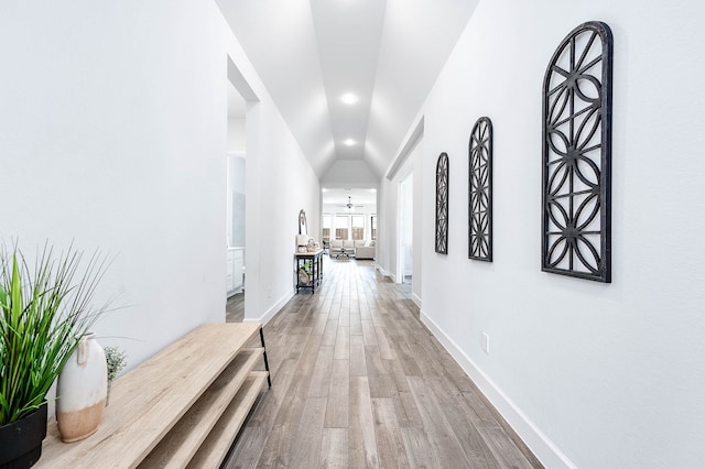 hallway with an inviting chandelier, lofted ceiling, and hardwood / wood-style floors