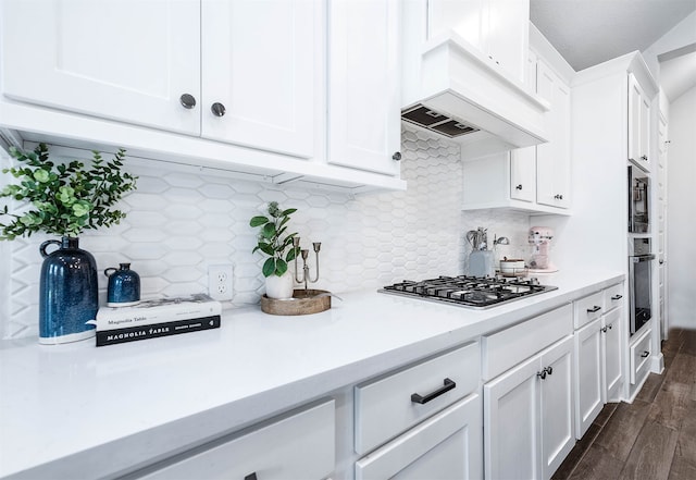 kitchen with white cabinetry, backsplash, stainless steel appliances, and custom range hood