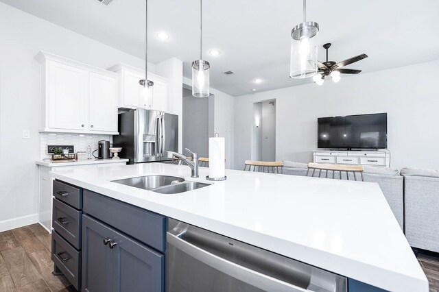 kitchen featuring white cabinetry, appliances with stainless steel finishes, dark hardwood / wood-style floors, hanging light fixtures, and sink