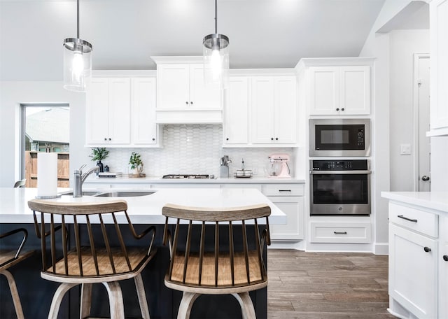 kitchen with hanging light fixtures, white cabinets, built in microwave, and oven