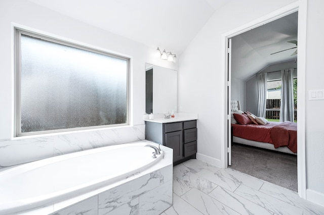 bathroom with ceiling fan, tiled tub, vanity, and lofted ceiling