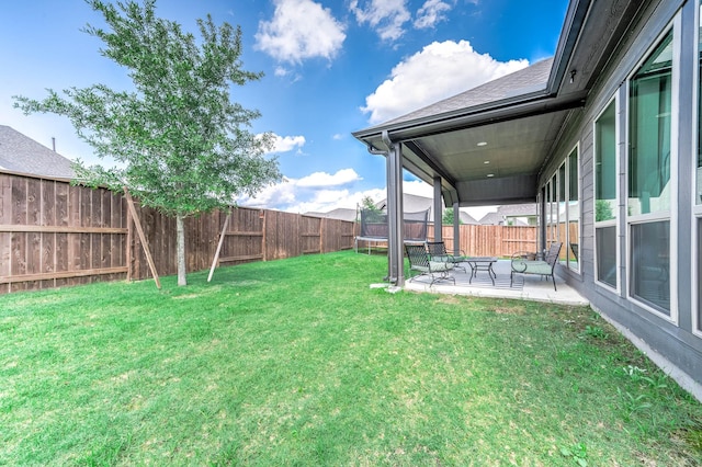 view of yard with a trampoline and a patio area