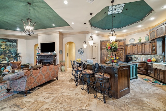 kitchen featuring a center island, dark stone countertops, hanging light fixtures, a breakfast bar, and a tray ceiling