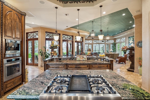 kitchen with a center island, french doors, dark stone countertops, a raised ceiling, and stainless steel oven