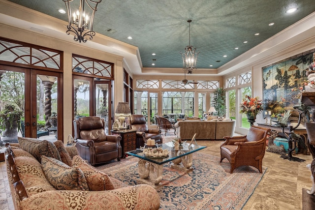 living room featuring crown molding, french doors, a towering ceiling, a tray ceiling, and an inviting chandelier