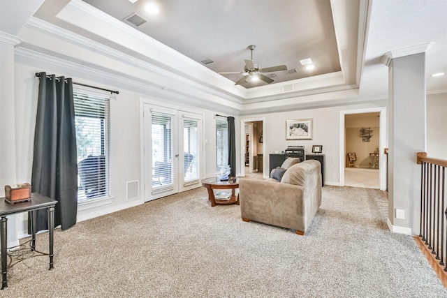 carpeted living room featuring a tray ceiling, ceiling fan, and crown molding