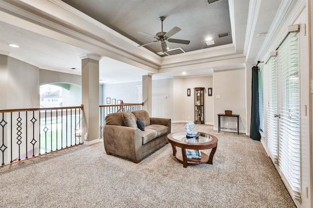 carpeted living room featuring a raised ceiling, ornate columns, and ornamental molding