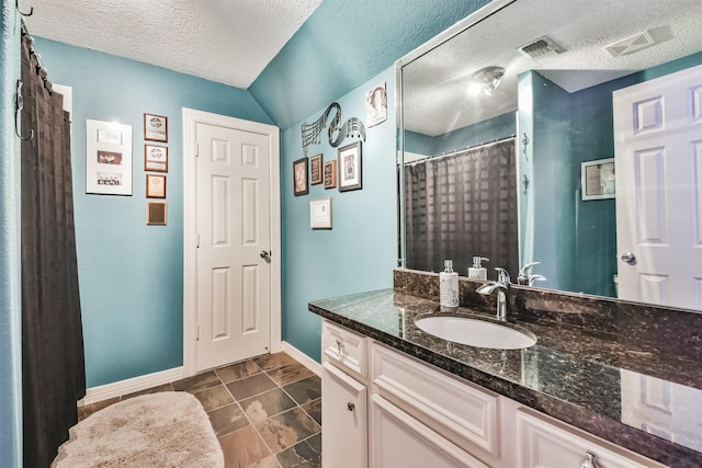 bathroom with tile patterned floors, vanity, and a textured ceiling