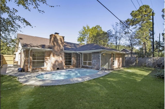 rear view of property featuring a lawn and a fenced in pool