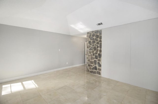 tiled empty room featuring lofted ceiling