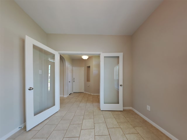 tiled empty room featuring french doors