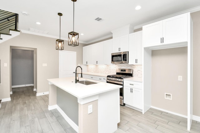 kitchen with stainless steel appliances, sink, pendant lighting, a center island with sink, and white cabinets